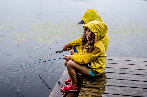 Photo of Young girl and boy fishing under rain