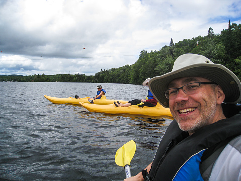 A man taking a selfie while on kayak on lake Sept-Iles (Portneuf) and two others kayaks