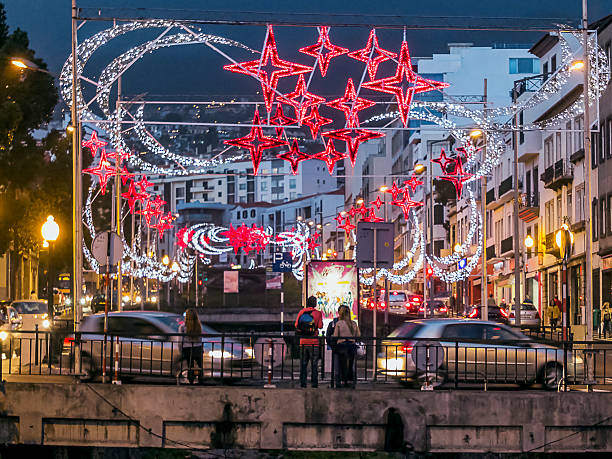 Funchal Funchal, Portugal - December 10, 2013: Tourists standing on a busy bridge in Funchal. Red and white Christmas decorations hangs over the bridge. funchal christmas stock pictures, royalty-free photos & images