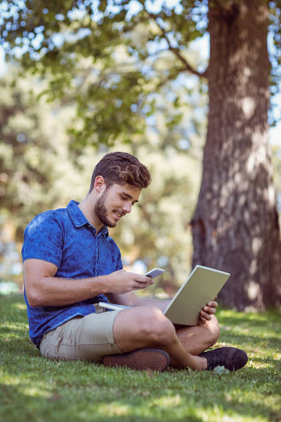 istock Hipster using laptop and phone in the park 482559494
