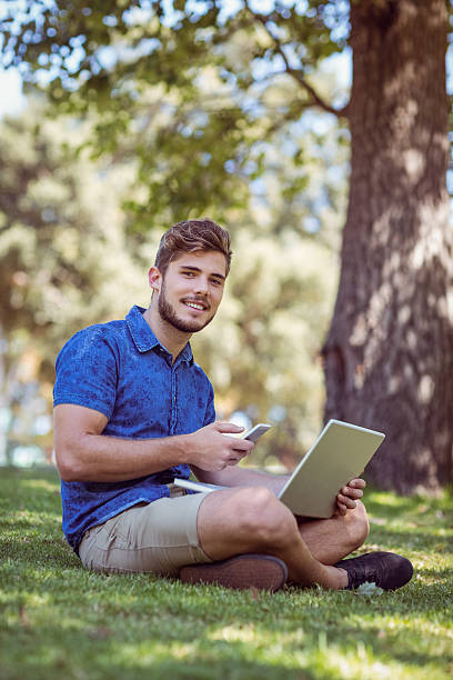 istock hipster using laptop and phone in the park 482559500