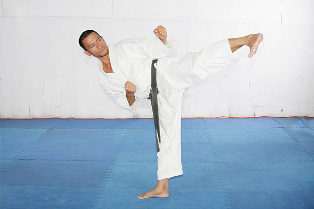 homem praticando artes marciais na academia de ginástica - sports clothing kicking high up tall - fotografias e filmes do acervo