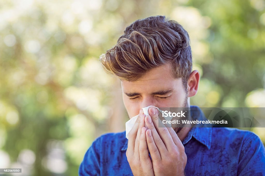 Handsome hipster blowing his nose Handsome hipster blowing his nose on a sunny day Men Stock Photo