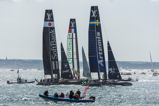 Rio de Janeiro, Brazil – September 10, 2023: several sailors in the 420 class sailboat regatta on a very windy and rainy day in Guanabara Bay during the Rio de Janeiro sailing week. In the background the city of Rio de Janeiro financial district.