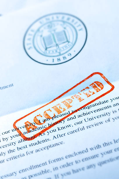 University Application Acceptance Notification Letter with ACCEPTED Stamp An acceptance letter from a university application. An university application form together with the letter of acceptance with a red rubber stamp of "Accepted" on a table top still life. Photographed close-up in vertical format with selected focus on the rubber stamp impression. college acceptance letter stock pictures, royalty-free photos & images