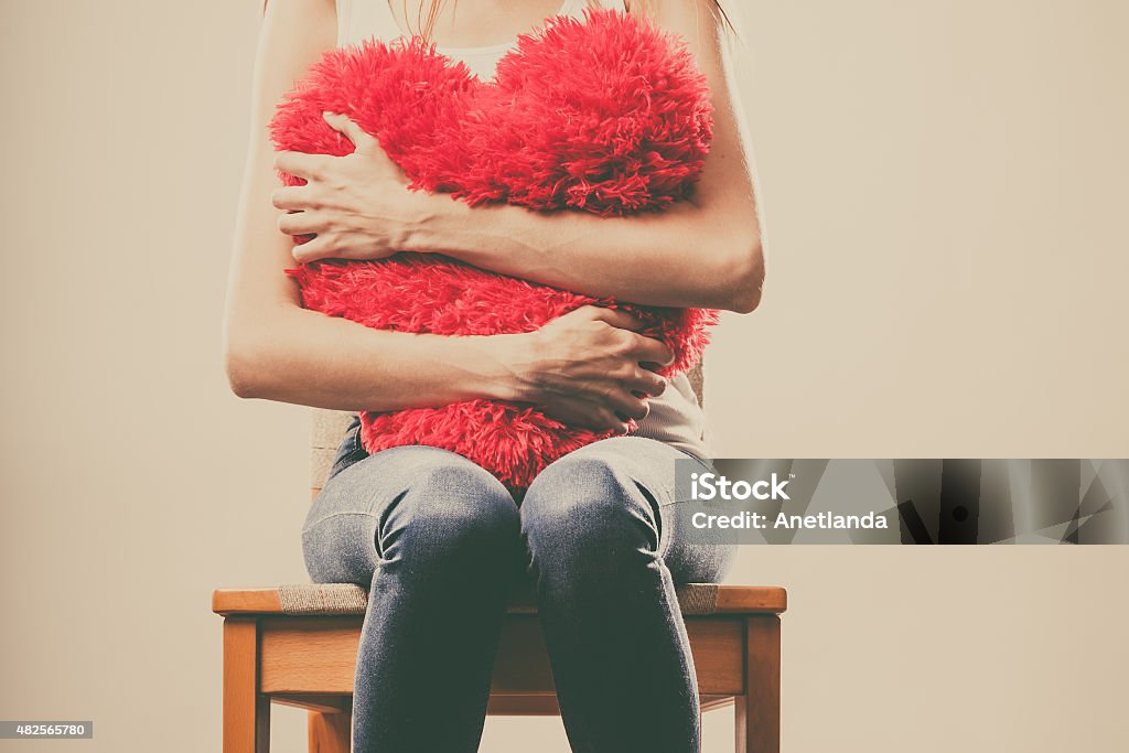 Sad unhappy woman holding red heart pillow Broken heart love concept. Sad unhappy woman hugging red heart pillow Broken Heart Stock Photo