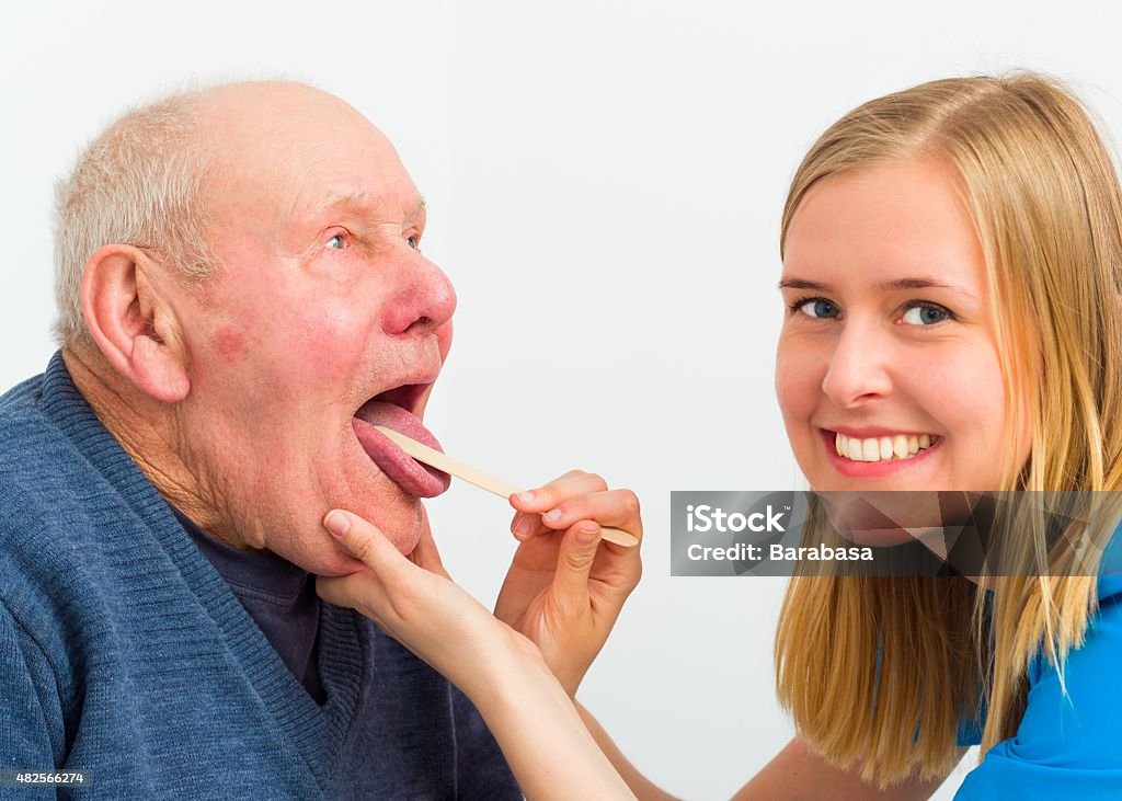 Elderly Man With Throat Pain Young doctor examining elderly patient's painful throat. 2015 Stock Photo