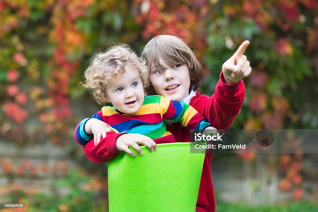 Funny baby girl and her brother playing with laundry basket Funny little baby girl and her brother playing together in the garden with a laundry basket 12-17 Months Stock Photo