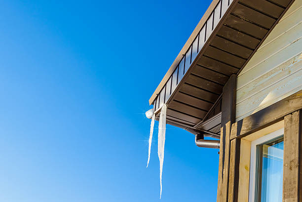 telhado de casa com pendurar icicles sobre fundo de céu azul - tony snow fotos imagens e fotografias de stock