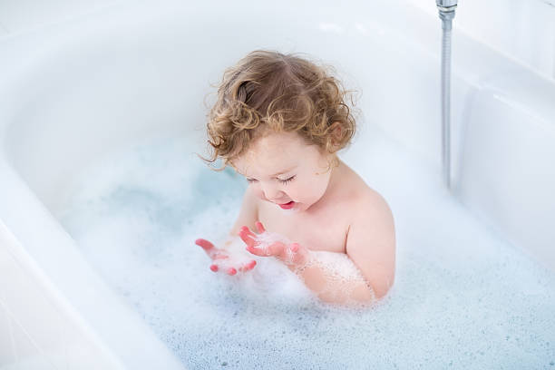 piccolo bambino divertente ragazza giocando con schiuma in vasca da bagno - bathtub child bathroom baby foto e immagini stock