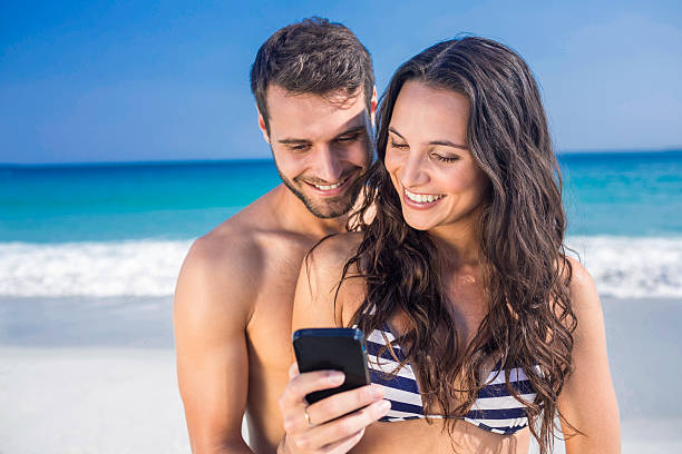 istock Happy couple using smartphone at the beach 482574102