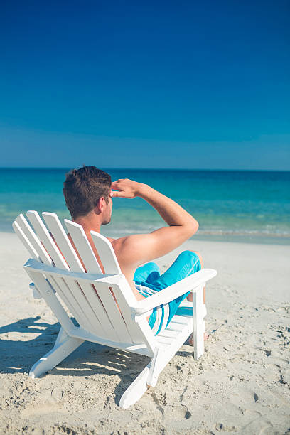 istock Man relaxing on deck chair at the beach 482576794