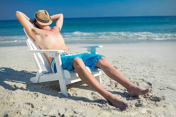 istock Man relaxing on deck chair at the beach 482576804