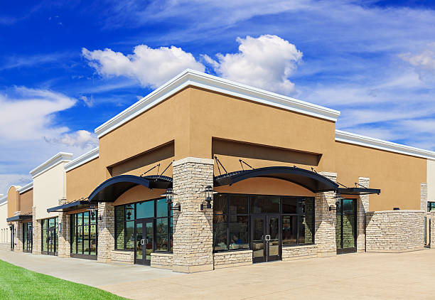 Brand New Strip Mall New commercial development featuring a street view of a Strip Mall with green grass, sidewalk and patio space. Blue sky and clouds are in the background. commercial real estate stock pictures, royalty-free photos & images