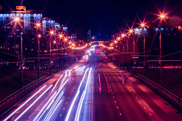 дорожного движения ночью город в ночь с фиолетовой и красной освещения - multiple lane highway стоковые фото и изображения