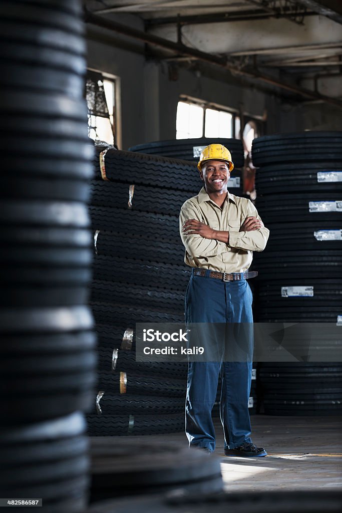 Man working in warehouse Mature man (50s) working in warehouse.  Truck tires in background. Tire - Vehicle Part Stock Photo