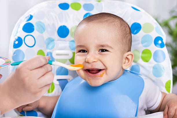istock Smiling happy adorable baby eating fruit mash 482587168