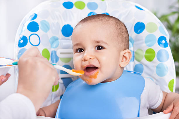istock Smiling happy baby eating with spoon 482587182