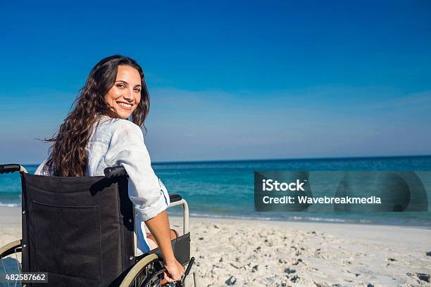Disabled Woman Looking At Camera Stock Photo - Download Image Now - Wheelchair, Beach, Vacations