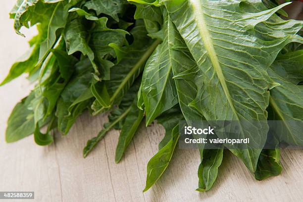 Chicory Catalogna With Tomatoes And Garlic On A Table Stock Photo - Download Image Now