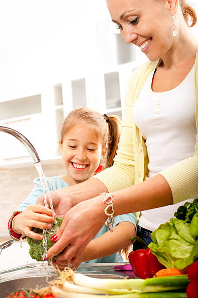 istock Little daughter and mother washing vegetables 482597363