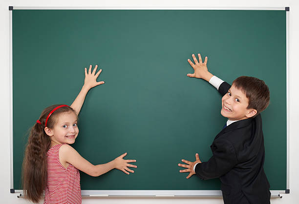 istock boy and girl write on school board 482597806