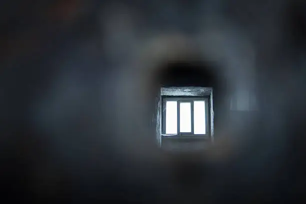 View into a prison cell, through the eye-hole. The impression is of the eye looking through the hole.