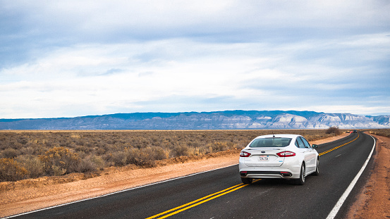White Sands, NM, USA - February 17, 2014: White Ford Fusion driving on highway through desert in New Mexico.