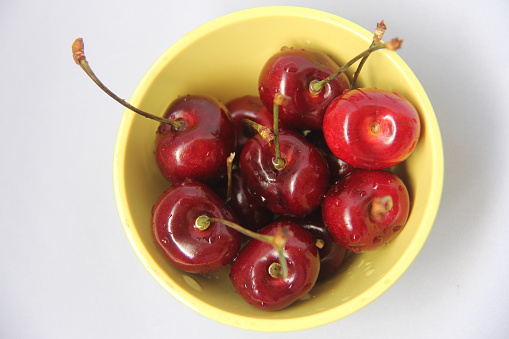 Freshly picked cherries in a yellow bowl
