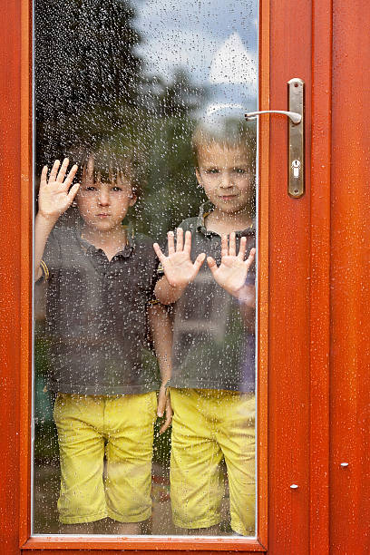 istock Two little boy, wearing same clothes looking through big glass 482604876