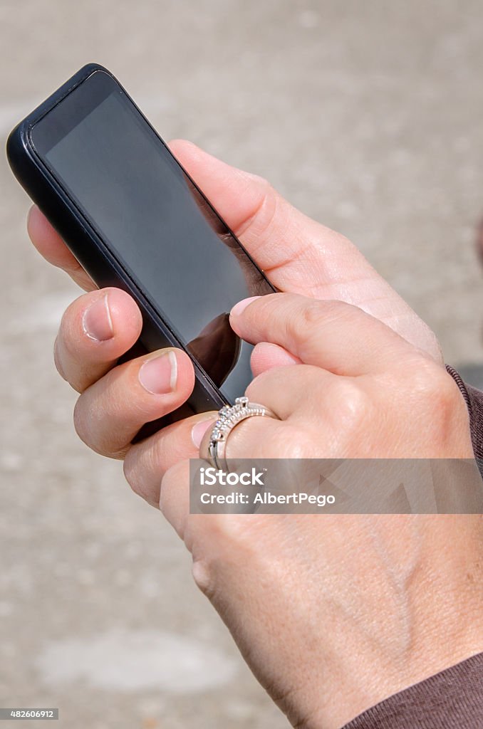 Young Woman Using her Smartphone Outdoor Young woman surfing the internet with her touchscreen smartphone. 2015 Stock Photo