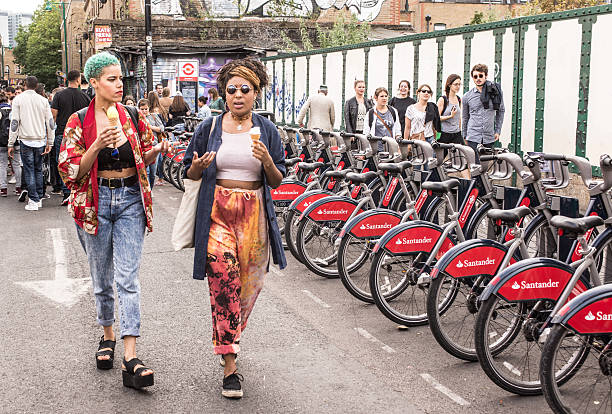 London, UK - July 12, 2015: Two hipster girls dressed in cool londoner style walking in Brick lane, a street popular among young trendy people.