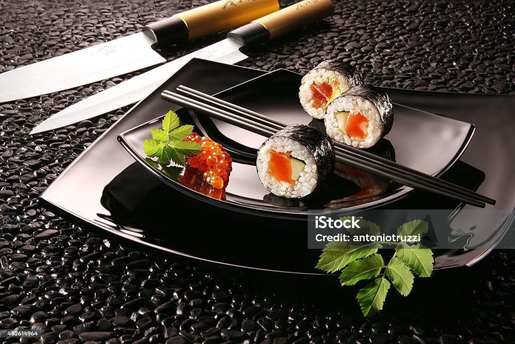 Sushi futomaki Typical Japanese food with knives on a black plate 2015 Stock Photo