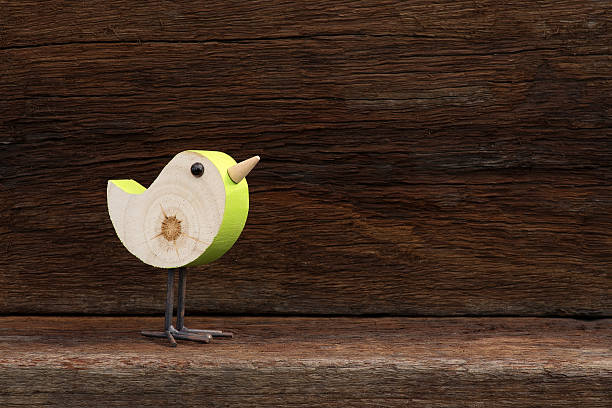Wooden green toy bird figure symbol on old rough background with copy space