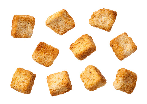 Ten Individual Croutons  photographed at different angles.  Croutons are small pieces of fried or toasted bread, served with soup, or used as a garnish in salads.  These croutons are softly lit from the upper right.  They can easily be lifted off of the page and incorporated into any project that has food in it. The image is a cut out, isolated on a white background.