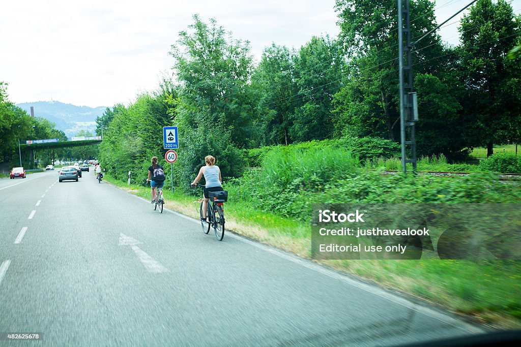 Over taking cycling people on street in Lindau Lindau, Germany - July 11, 2015: Over taking cycling people on street in Lindau at Bodensee in Bavaria. Summertime shot, Traffic is ruling ahead. 2015 Stock Photo