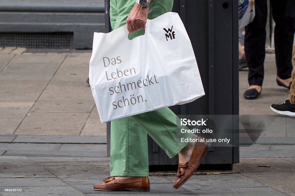 WMF plastic bag shopping street sale Wiesbaden, Germany - July 28, 2015: An unrecognisable pedestrian with a shopping bag of WMF walking by in a shopping street in the city center of Wiesbaden. WMF (Wuerttembergische Metallwarenfabrik) is a German silverware manufacturer, headquartered at Geislingen an der Steige, Germany 2015 Stock Photo