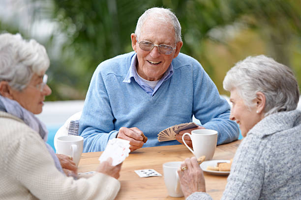 Care for a wager ladies? A group of senior citizens playing cards together hand of cards stock pictures, royalty-free photos & images