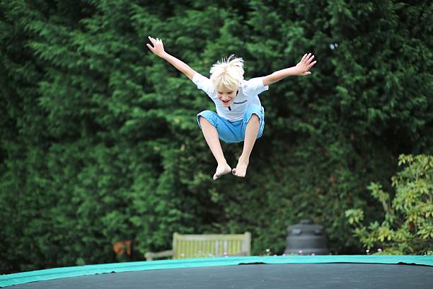 istock Happy boy plays outdoors in garden jumping on trampoline 482631911