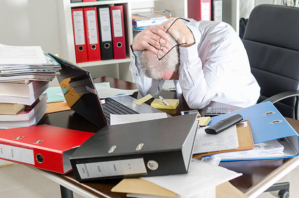Stressed businessman Stressed businessman holding his head in his hands cluttered stock pictures, royalty-free photos & images