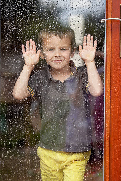 istock Little boy behind the window in the rain 482634918