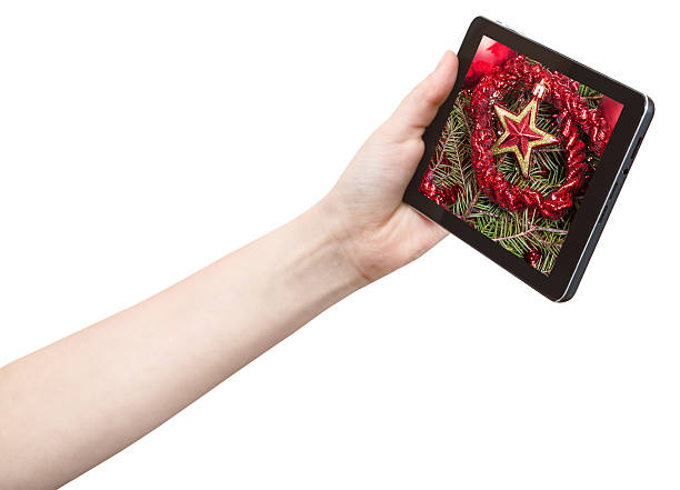 istock hand holds tablet pc with red star and tinsel 482643294