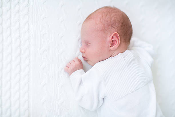 istock Cute newborn baby boy sleeping on a white knitted blanket 482643709