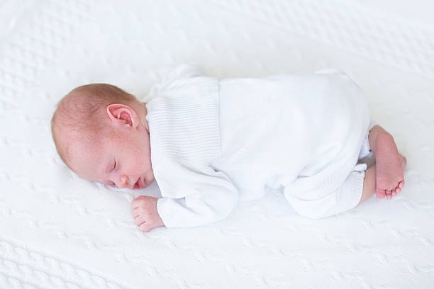 istock Tiny newborn baby sleeping on his tummy at knitted blanket 482643799