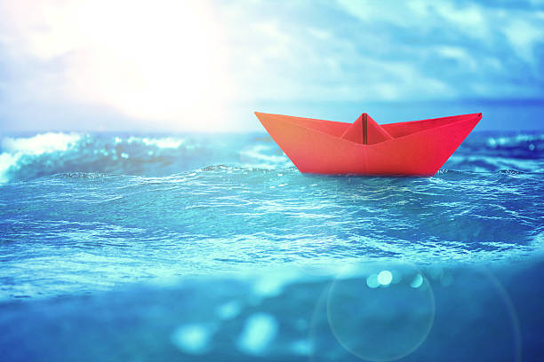 istock close up sea water surface with yellow paper boat 482644502