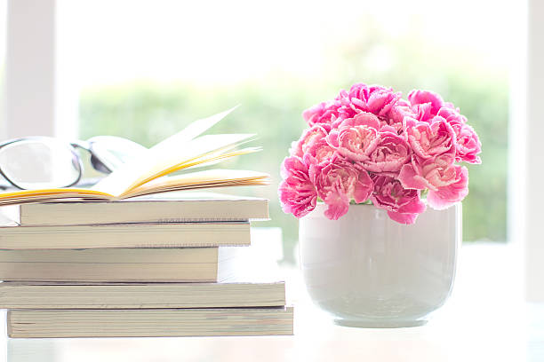 istock fresh pink carnation flower with books background 482645070