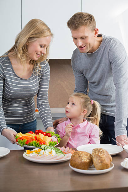 Happy parents with daughter having meal in kitchen