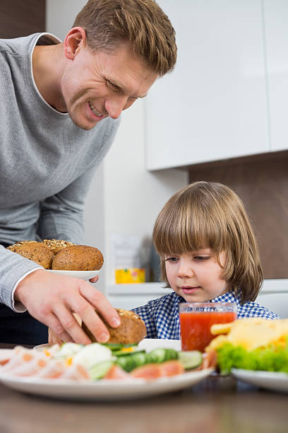 istock Happy father serving meal to son at table in kitchen 482645441