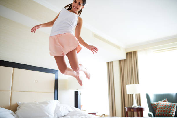 istock Angled view of woman jumping on bed. 482645518