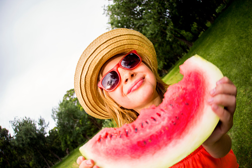 Girl with hat holding slice of watermelon